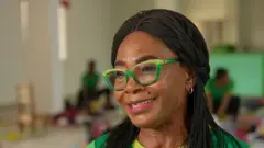 Photo en gros plan de Nonye Nweke portant des lunettes vertes. Elle a les cheveux longs.