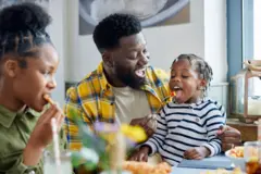 Famille de trois personne à table en train de manger