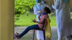 A resident reacts as a health worker collects a swab sample for the Covid-19 coronavirus