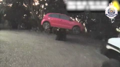 Um carro vermelho suspenso no ar por uma empilhadeira