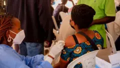 Umugore urimo guhabwa urukingo rwa Covid ku isoko rya Ziniya mu karere ka Kicukiro mu mujyi wa Kigali, ku itariki ya 6/1/2022