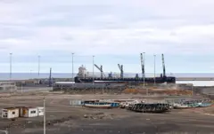 Un gran buque de carga se observa detrás de embarcaciones de migrantes apiladas en el puerto de Granadilla de Abona, en la isla de Tenerife, en el archipiélago de las Islas Canarias, España, el 6 de mayo de 2026.
