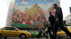Tahran'da bir duvar resminin önünden geçen trafik. Bir erkek ve bir kadın da yürürken görülüyor.