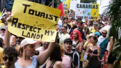 Protesters in Santa Cruz de Tenerife hold placards against mass tourism in Spain's Canary Islands. Photo: 20 April 2024