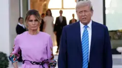  الرئيس الأمريكي السابق دونالد ترامب يقف بجانب زوجته ميلانيا
