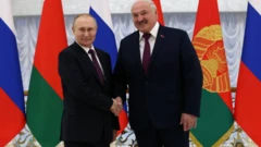 Vladimir Putin (i bubamfu) na Alexander Lukashenko barakorana mu ntoke imbere y'inama yabo ku Kirimba citiriwe ukwikukira i  Minsk