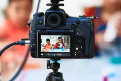 Duas crianças fazendo trabalho manual aparecem em tela de câmera