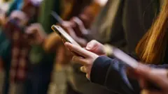 Um grupo de jovens olhando para seus smartphones.