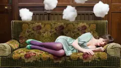 Mulher dorme em um sofá e nuvens acima dela representam ideias