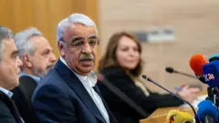 DEM Parti milletvekili Mithat Sancar basın toplantısında konuşuyor. Önünde birçok mikrofon var.