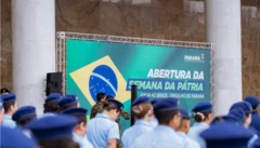 Estudantes de uniforme em escola cívico-militar do Paraná, com placa do programa ao fundo e bandeira do Brasil