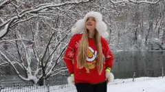 நியூயார்க் நகரின் சென்ட்ரல் பார்க்கில் பனிப்பொழிவை ரசிக்கும் பெண் 