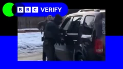 車に移民当局の職員2人が近づく様子をとらえた動画のスクリーンショット