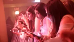 Garotas mexem em seus celulares