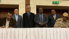 أحد قادة المحتجين (في اليسار) وممثل المجلس العسكري (في اليمين) يوقعان الاتفاق
