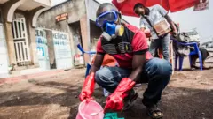 DR Congo health worker mixes water and chlorine in Goma