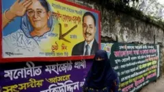 একটি দেয়ালে শেখ হাসিনা ও হুসেইন মুহাম্মদ এরশাদের ছবিসহ নির্বাচনি ব্যানার যেখানে লাঙলে ভোট দেওয়ার আহ্বান জানানো হয়েছে, সামনে দিয়ে হেঁটে যাচ্ছেন বোরকা পরা এক নারী