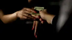এক গণিকার হাতে অর্থ তুলে দিচ্ছে একটি পুরুষ হাত