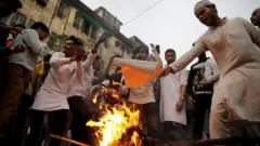 Penduduk membakar patung Perdana Menteri Narendra Modi di Kolkata, India.