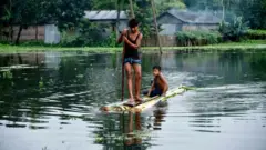 बाढ़ के पानी पर नाव चलाते बच्चे