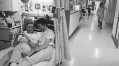 ผู้ชายสองคนนอนบนเตียงผู้ป่วย