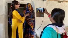 नाज़नी रिज़वी (बाएं) और मीरा देवी (दाएं) एक ग्रामीण महिला का इंटरव्यू लेते हुए