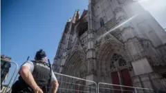 A police officer stares up at the charred front of the cathedral in Nantes