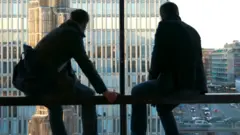 Dois homens sentados dentro de prédio, na contraluz, observando rua em Estocolmo