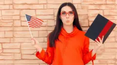 A young woman whistling, holding an American flag