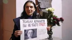 Девушка с плакатом "Убивая журналистов вы не убьете правду" у мемориальной доски в честь журналистки Анны Политковской на здании редакции "Новой газеты" в Потаповском переулке. Политковская была убита в Москве 7 октября 2006 года