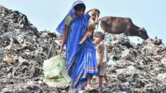 કચરો વીણતાં એક મહિલા અને બાળકો