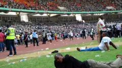 Job-seekers lie on the pitch after a stampede in Abuja National Stadium, where thousands of job-seekers came to apply for work at the Nigerian immigration department, in Abuja, on March 15, 2014.