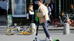 Una mujer montada en un monopatín eléctrico en París.