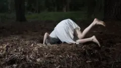 Menina com cabeça dentro de buraco