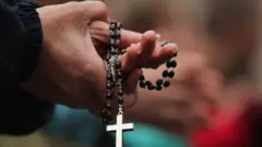 Persona rezando con un rosario en la mano