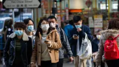 Residents seen wearing surgical masks while crossing the road in Wuhan, the epicentre of the coronovirus outbreak