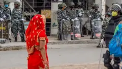 Fila de agentes de la policía y una mujer india vestida de rojo