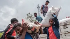 مدنيون نزحوا بسبب القتال في شمالي إثيوبيا يحملون الطعام والإمدادات من شاحنة في مدرسة في ديسي، إثيوبيا، في 23 أغسطس / آب 2021