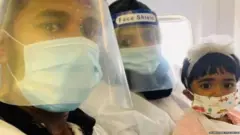 ਤਸਵੀਰ ਵਿੱਚ ਮਾਂ ਅਮਿਨਾ ਸ਼ਰੀਨ ਦੀ ਗੋਦ ਵਿੱਚ ਬੈਠੀ ਸ਼ਰਫੂਦੀਨ ਦੀ ਦੋ ਸਾਲਾ ਬੇਟੀ ਫਾਤਿਮਾ ਇੱਜ਼ਾ ਹੈਰਾਨ ਹੈ ਕਿ ਇਹ ਹੋ ਕੀ ਰਿਹਾ ਹੈ।