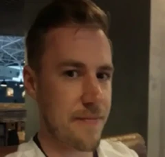 Imagem de Sergey Cherkasov olhando fixamente para a câmera usando roupa branca