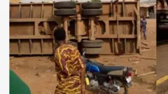 Aworan tirela to wo ati alupupu, ọkunrin kan duro lẹgbẹẹ alupuu naa, o kawọ pọnyin