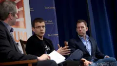 Max Levchin e Peter Thiel sentados, em uma conferência de negócios