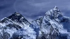Mount Everest. Two mountain peaks covered in snow. The sky is dark blue and it looks stormy.