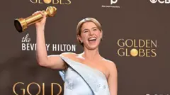 Jessie Buckley elindeki altın küre ödülünü kaldırmış halde gülerek poz veriyor