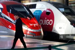 Um homem passando por dois trens de alta velocidade na estação de Málaga