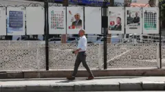 رجل يمر أمام ملصقات دعائية للانتخابات التشريعية الجزائرية في العاصمة الجزائرية، الجزائر، في 22 يونيو/حزيران 2026.