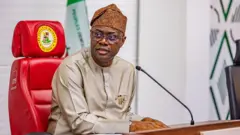 Gomina Seyi MAkinde joko lori aga alawọ pupa kan.