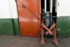 Adolescentes sentados atrás de grades 