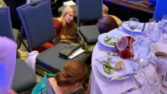 Image shows people hiding under tables at the venue