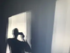 නිදන කාමර කවුළුව හරහා හිරු එළිය වැටෙන බිත්තියක් මත තරුණයෙක් තම සෙවනැල්ල ඡායාරූපයක් ගනිමින්